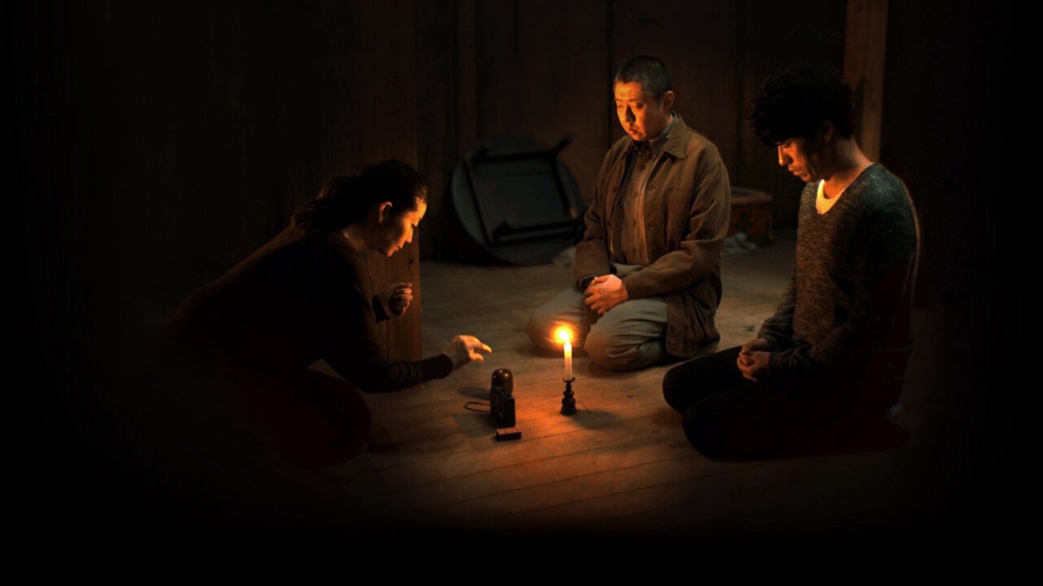 Dua laki-laki dan satu perempuan sedang duduk bersila mengelilingi sebuah lilin